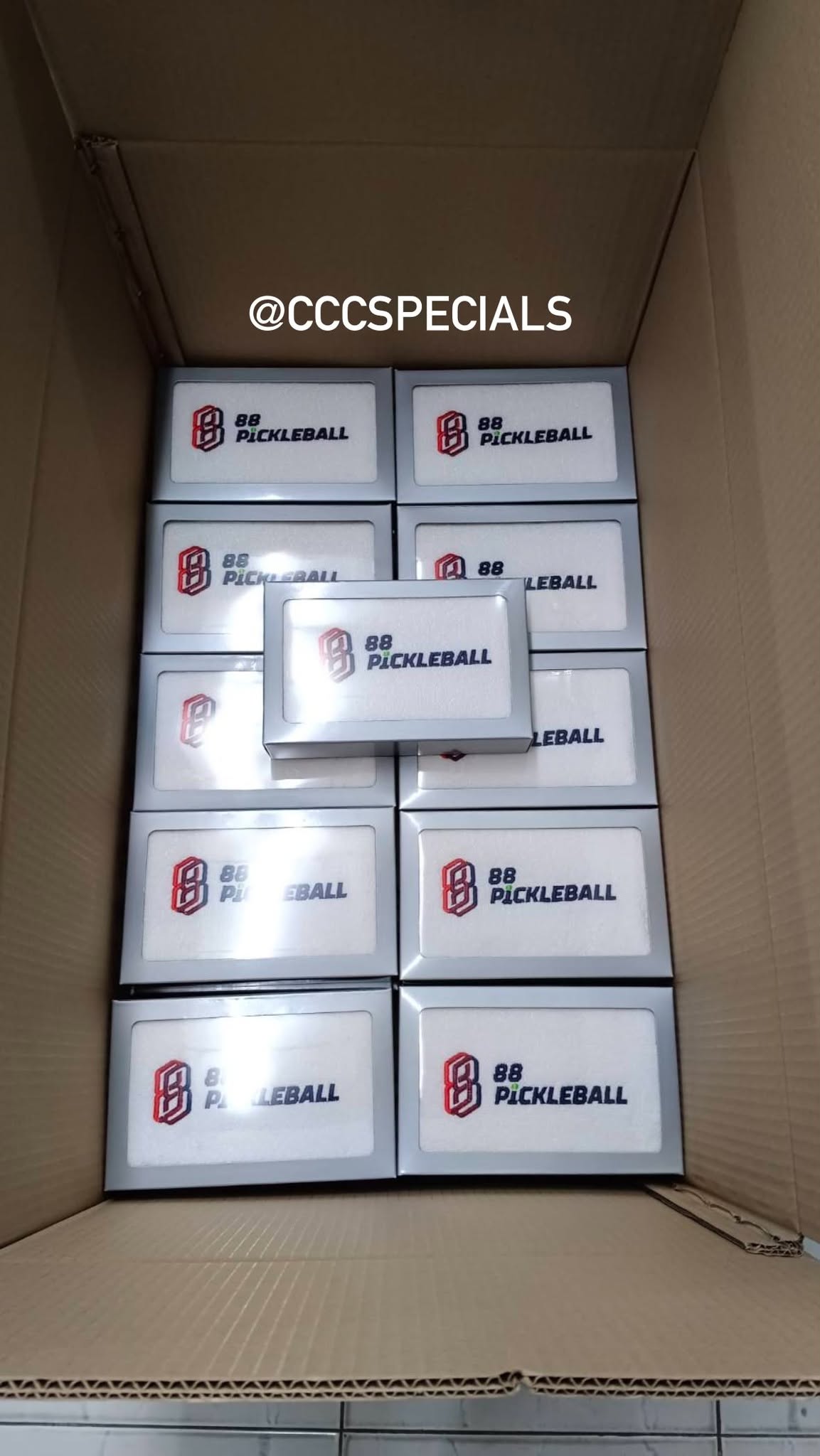 กล่องบรรจุภัณฑ์สินค้า 88 Pickleball บรรจุในกล่องกระดาษพร้อมจัดส่ง กล่องบรรจุภัณฑ์สีเงินพิมพ์โลโก้ 88 Pickleball วางเรียงกันอยู่ในกล่องกระดาษลูกฟูก