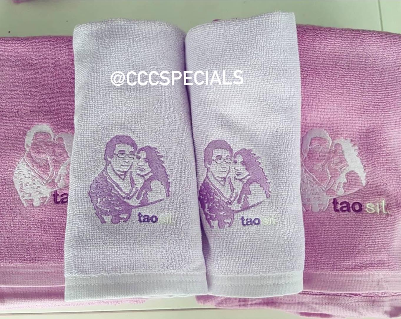 ผ้าขนหนูปักลายคู่รักพร้อมชื่อ tao sit ของขวัญพิเศษสั่งทำได้ ผ้าขนหนูสีชมพูและขาวปักลายคู่รักและข้อความ tao sit วางเรียงกันสวยงาม